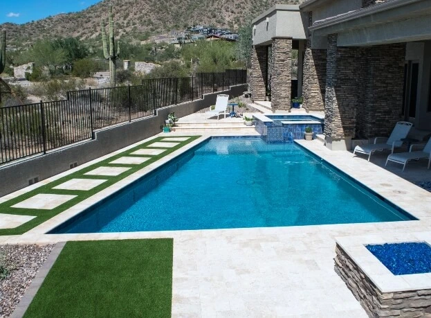 Custom Phoenix pool and raised spa with travertine decking below a desert hillside
